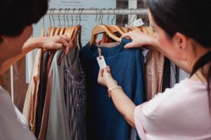 deux personnes examinant l'étiquette d'un vêtement en boutique — coût environnemental et affichage textile